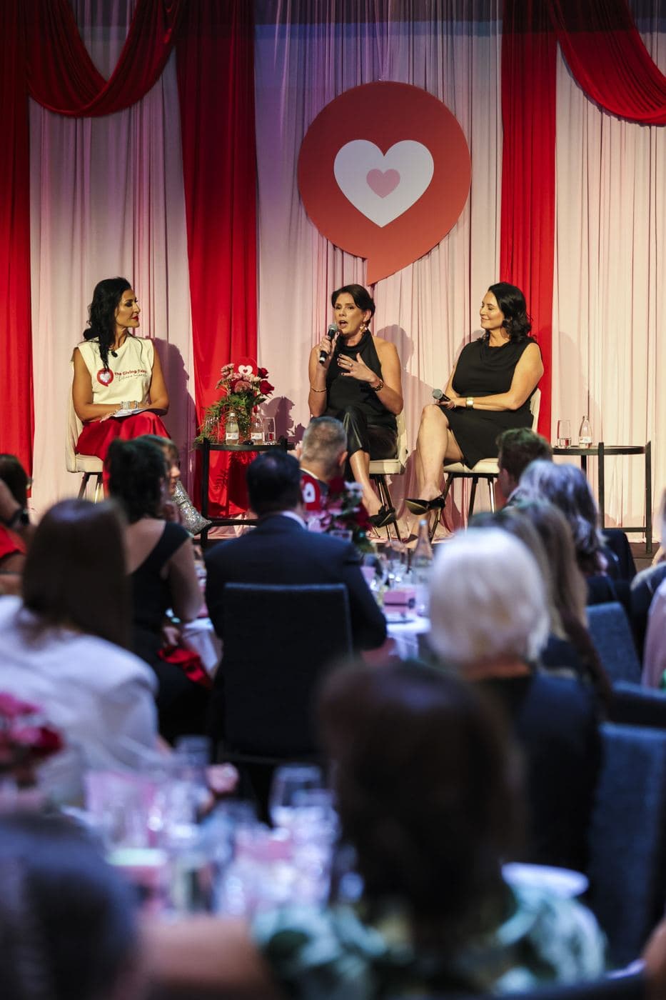 Gill Whelan, CEO of GILL WHELAN Projects, on stage at a philanthropy event
